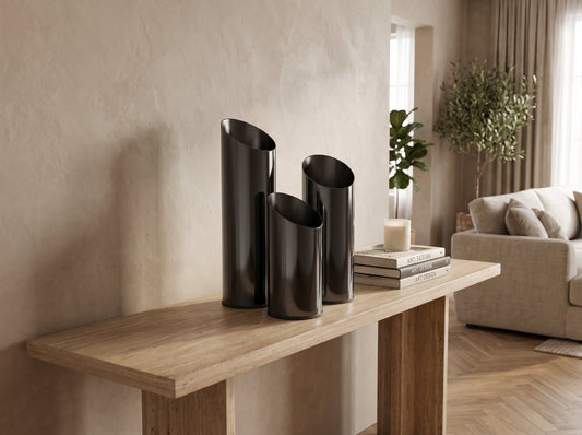 Three mirror-black slant-top vases on a console table